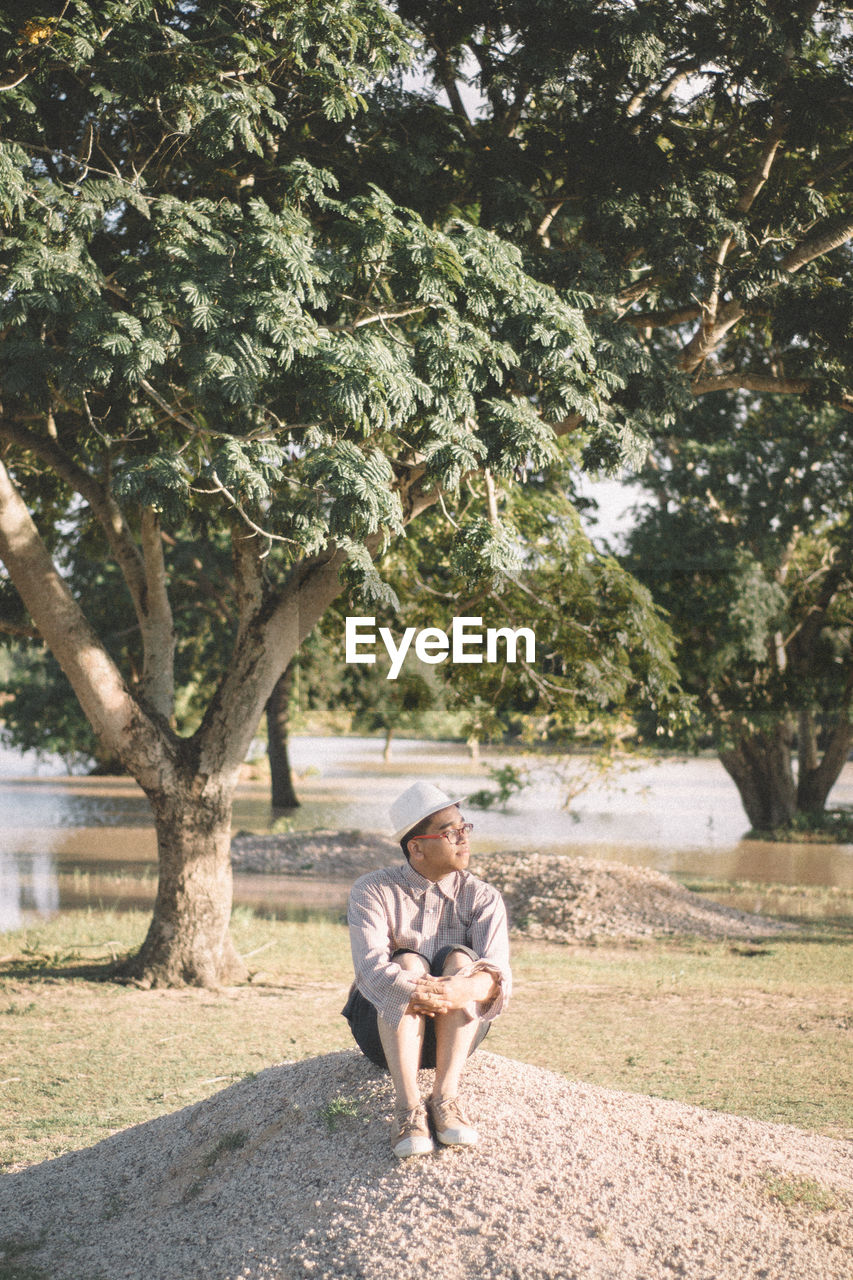 Full length of man sitting by tree at park