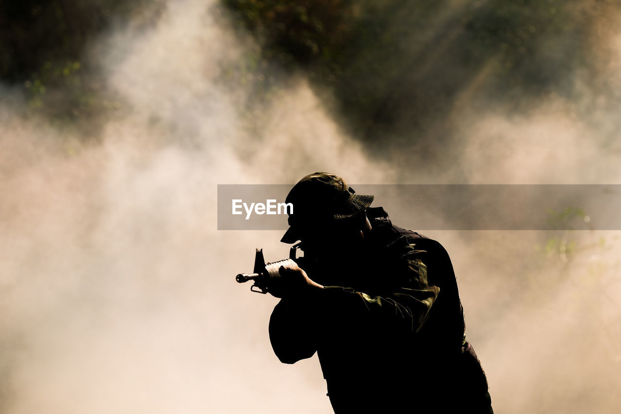 Silhouette soldier against smoke outdoors