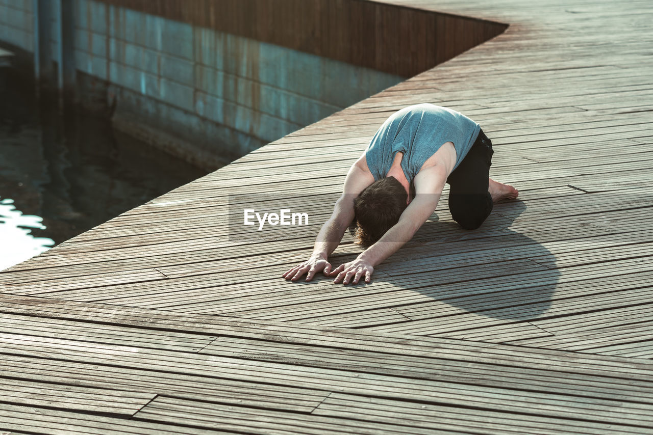 HIGH ANGLE VIEW OF PERSON RELAXING ON WOODEN FLOOR