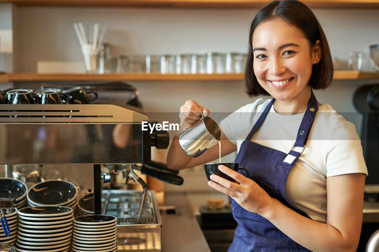 portrait of young woman using mobile phone while standing in cafe