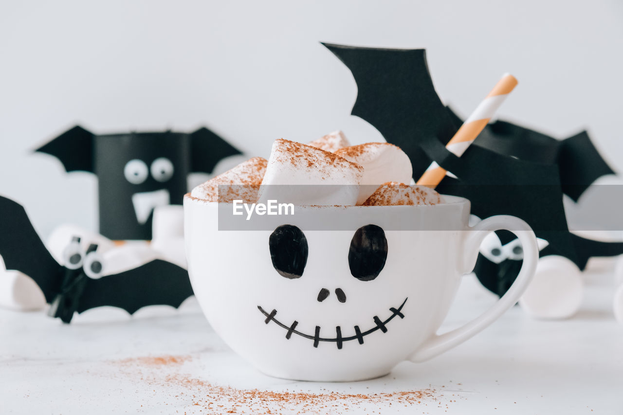 Painted white cup scary jacks face with marshmallows hot chocolate cacao drink diy for kids. 