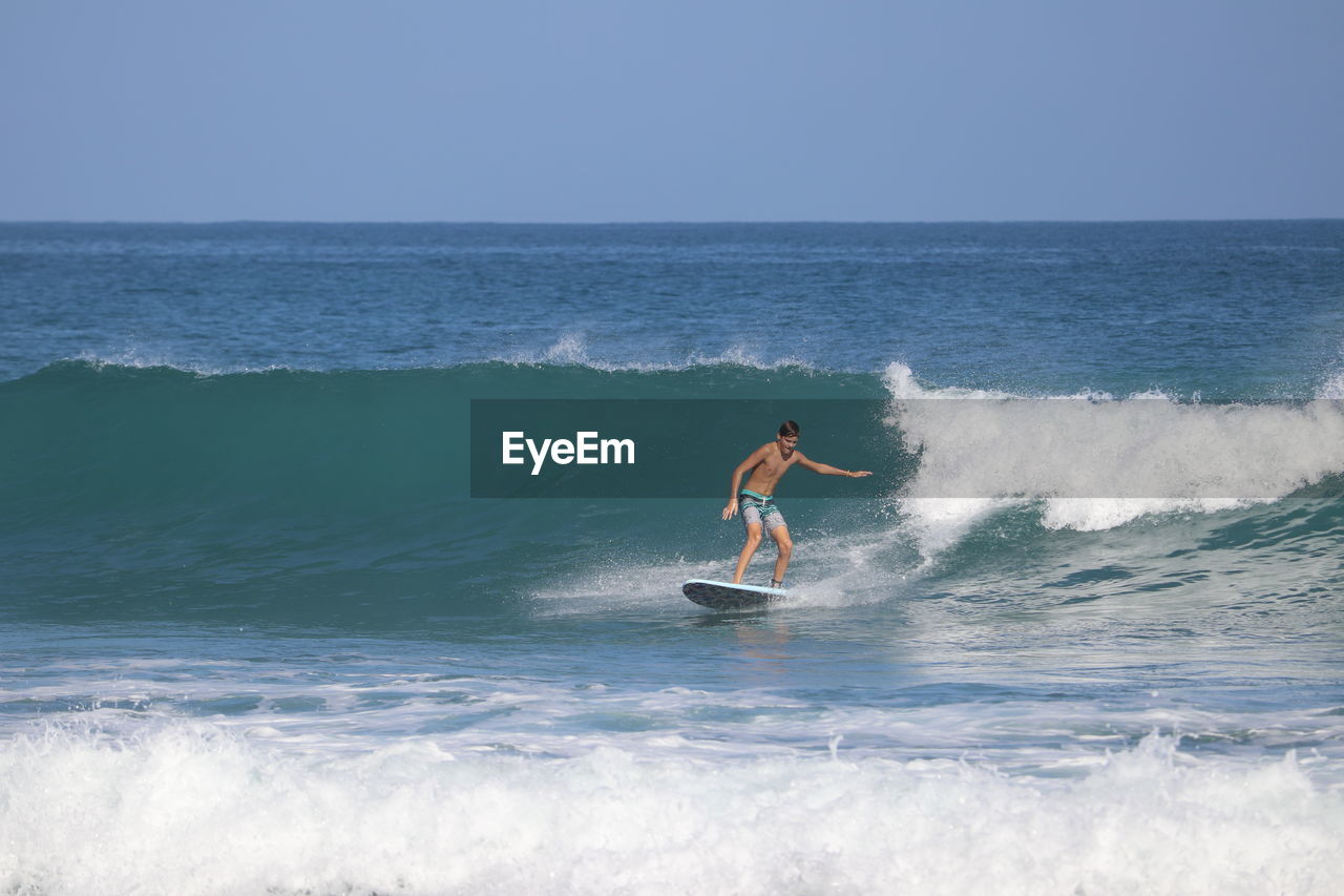 Man surfing in sea against sky