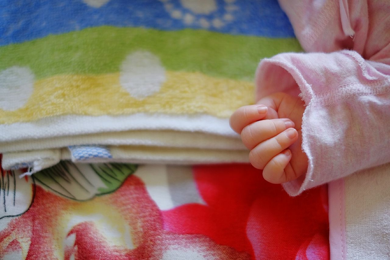 Cropped image of baby hand on bed