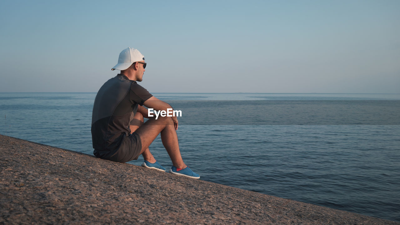 WOMAN LOOKING AT SEA AGAINST SKY