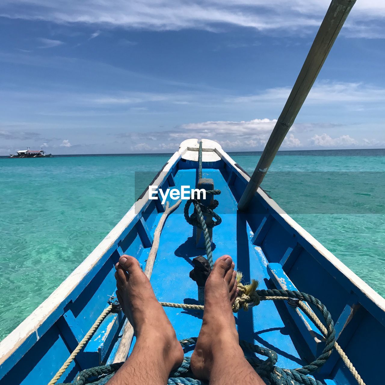 Low section of man at ships bow sailing in sea against sky