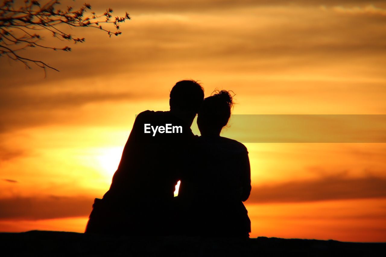 Silhouette couple against orange sky during sunset