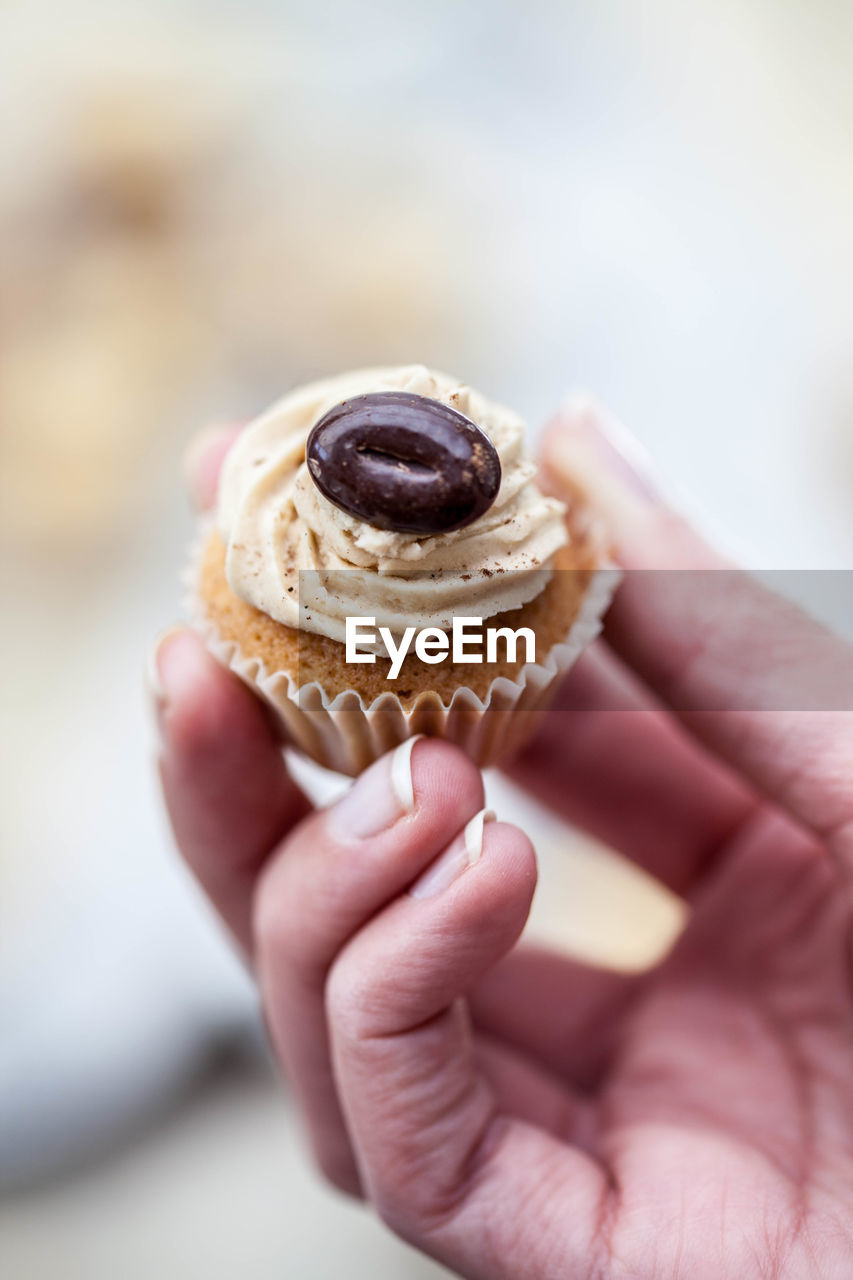 Cropped image of hand holding cupcake