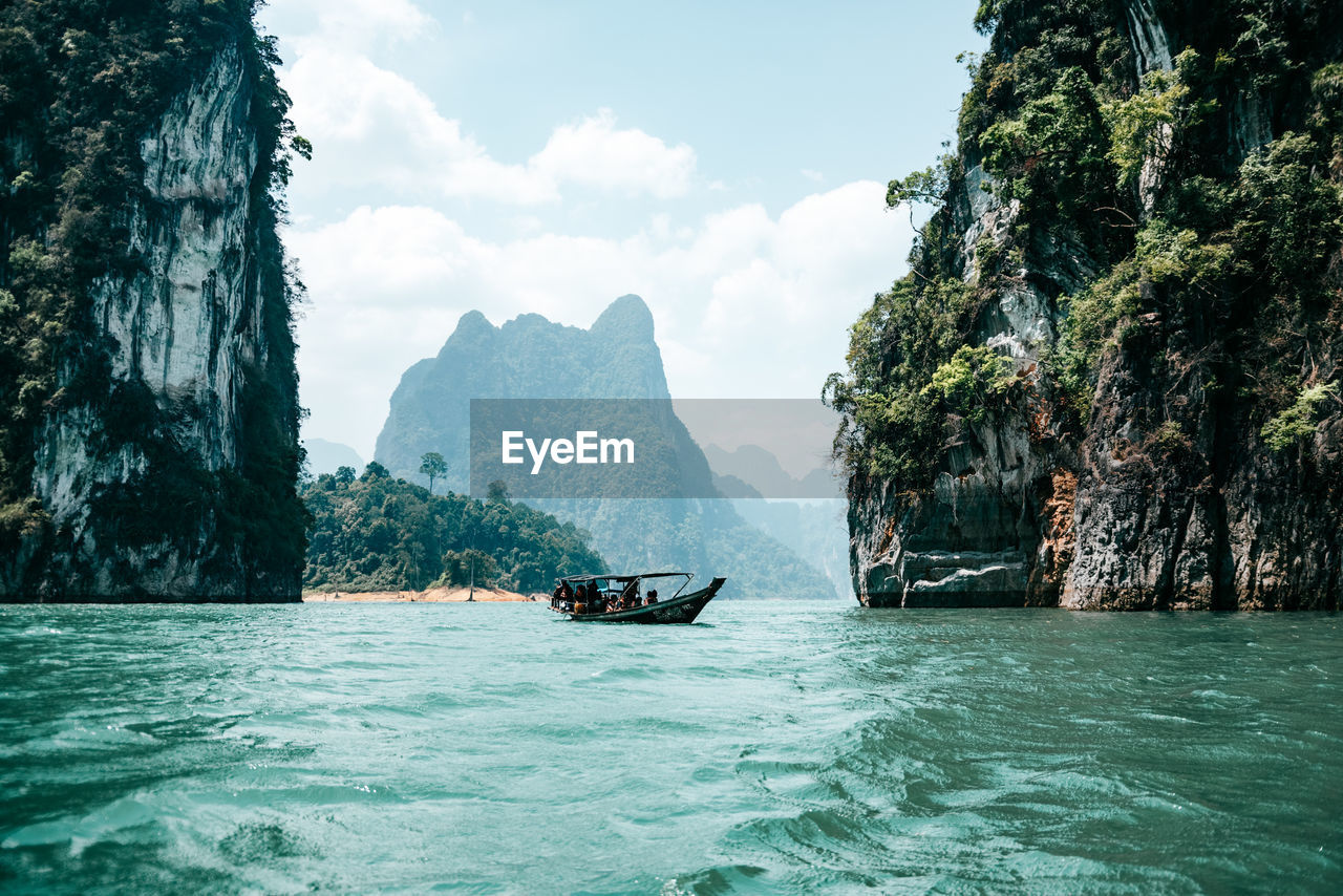 water, nautical vessel, scenics - nature, sea, beauty in nature, nature, travel, transportation, mountain, land, tree, sky, rock, bay, travel destinations, mode of transportation, vehicle, environment, boat, tropical climate, tranquility, day, tourism, vacation, trip, holiday, tranquil scene, outdoors, lagoon, idyllic, cloud, plant, island, beach, landscape, no people, cliff, turquoise colored, coast, rock formation, non-urban scene, bay of water, boating, mountain range, waterfront