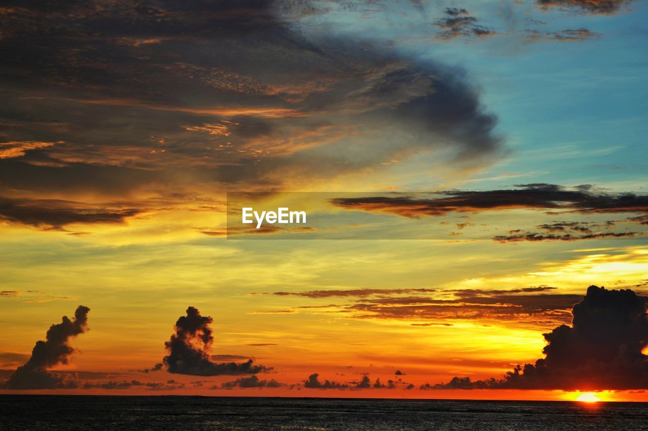 Scenic view of sea against dramatic sky during sunset