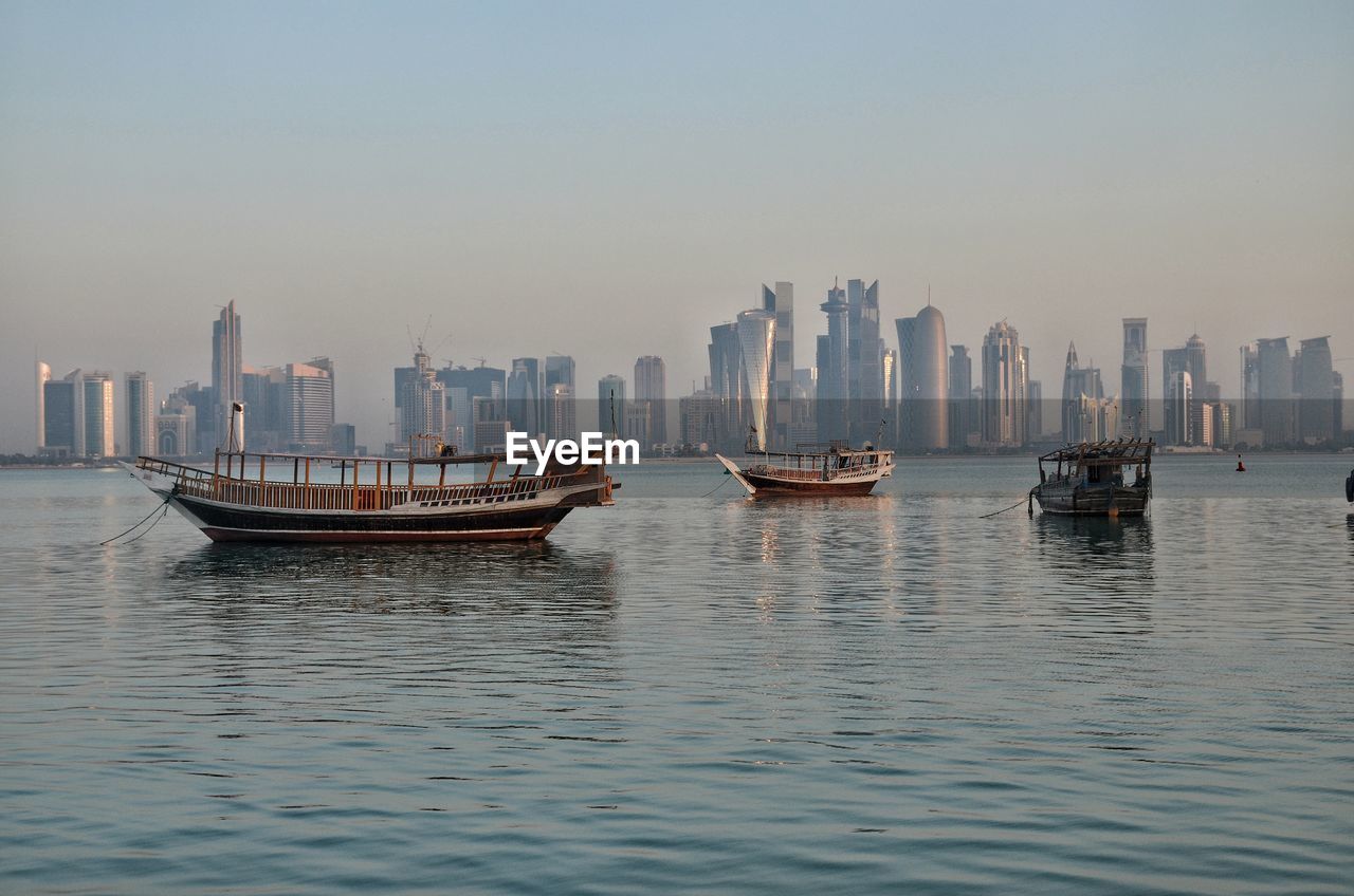 Boats in sea against buildings in city