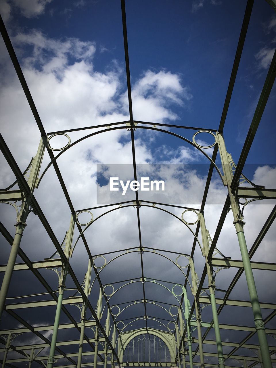 Low angle view of metallic built structure against cloudy sky