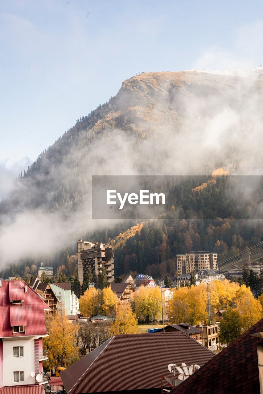 HIGH ANGLE VIEW OF TOWNSCAPE BY MOUNTAIN AGAINST SKY