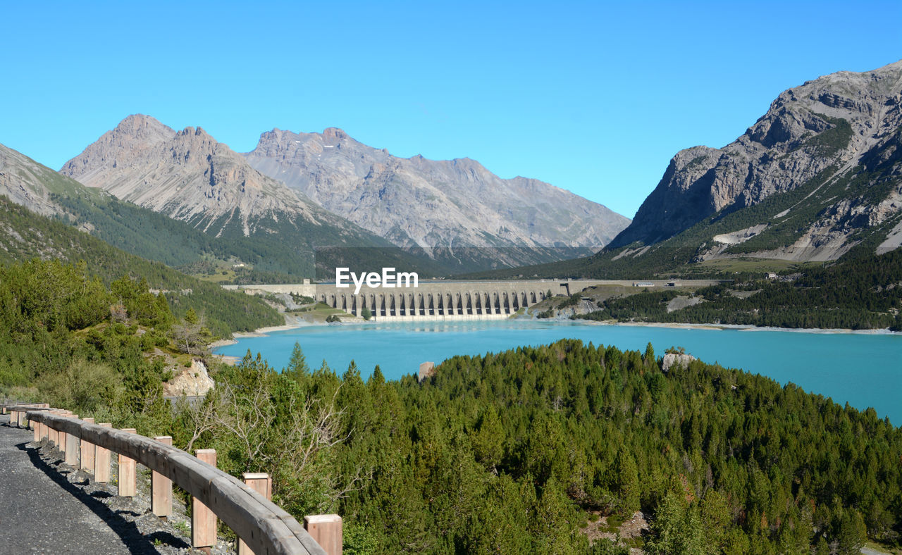 Scenic view of lake and mountains against clear blue sky