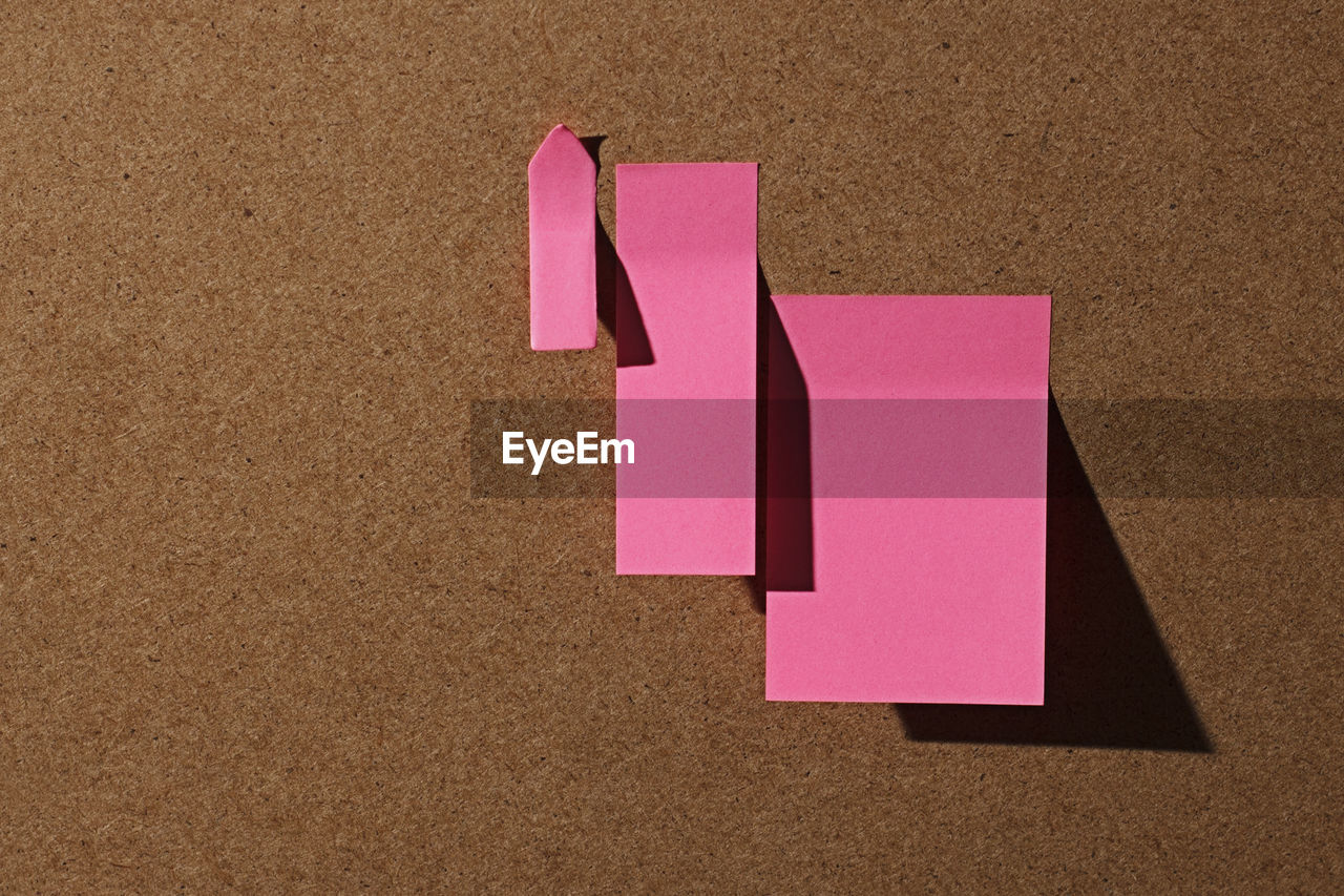 Pink office sticky notes on cork board with hard shadow with copy space