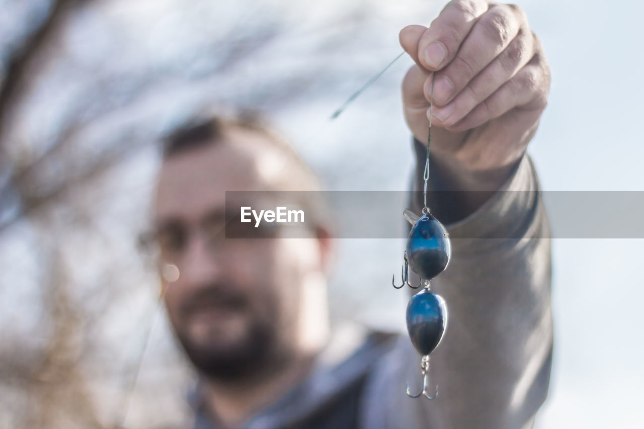 Close-up of man holding blue fishing bait