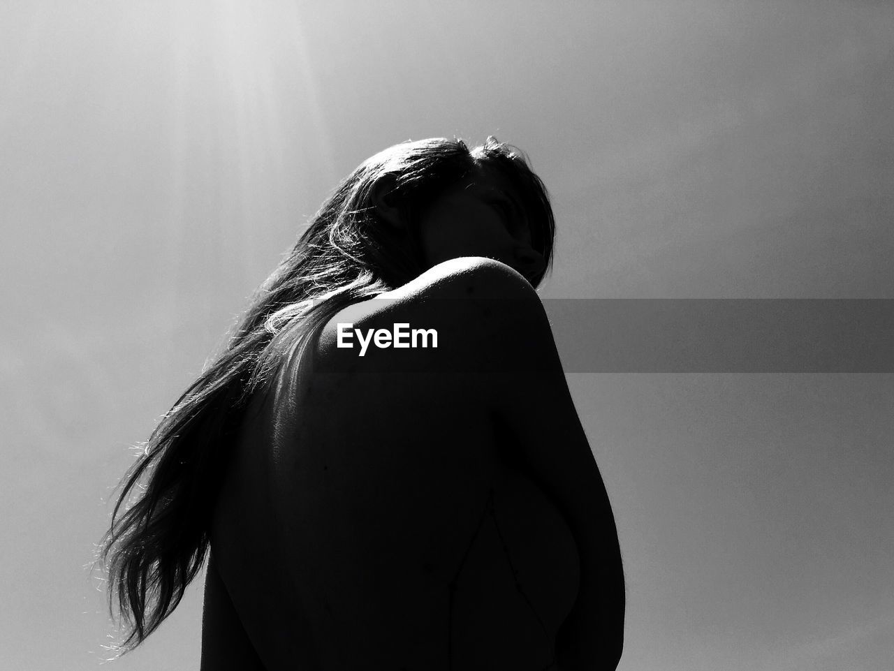 Low angle view of young woman standing against clear sky during sunny day