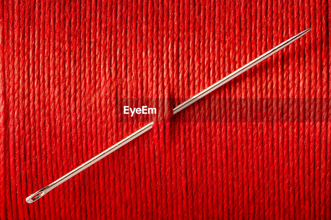 Close-up of sewing needle in red thread