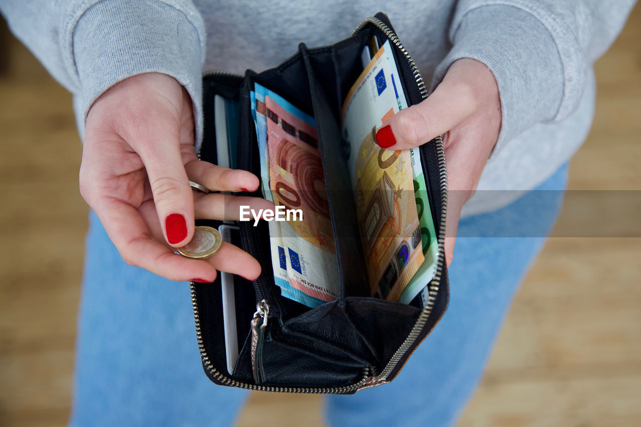 Midsection of woman holding coin and purse with paper currency