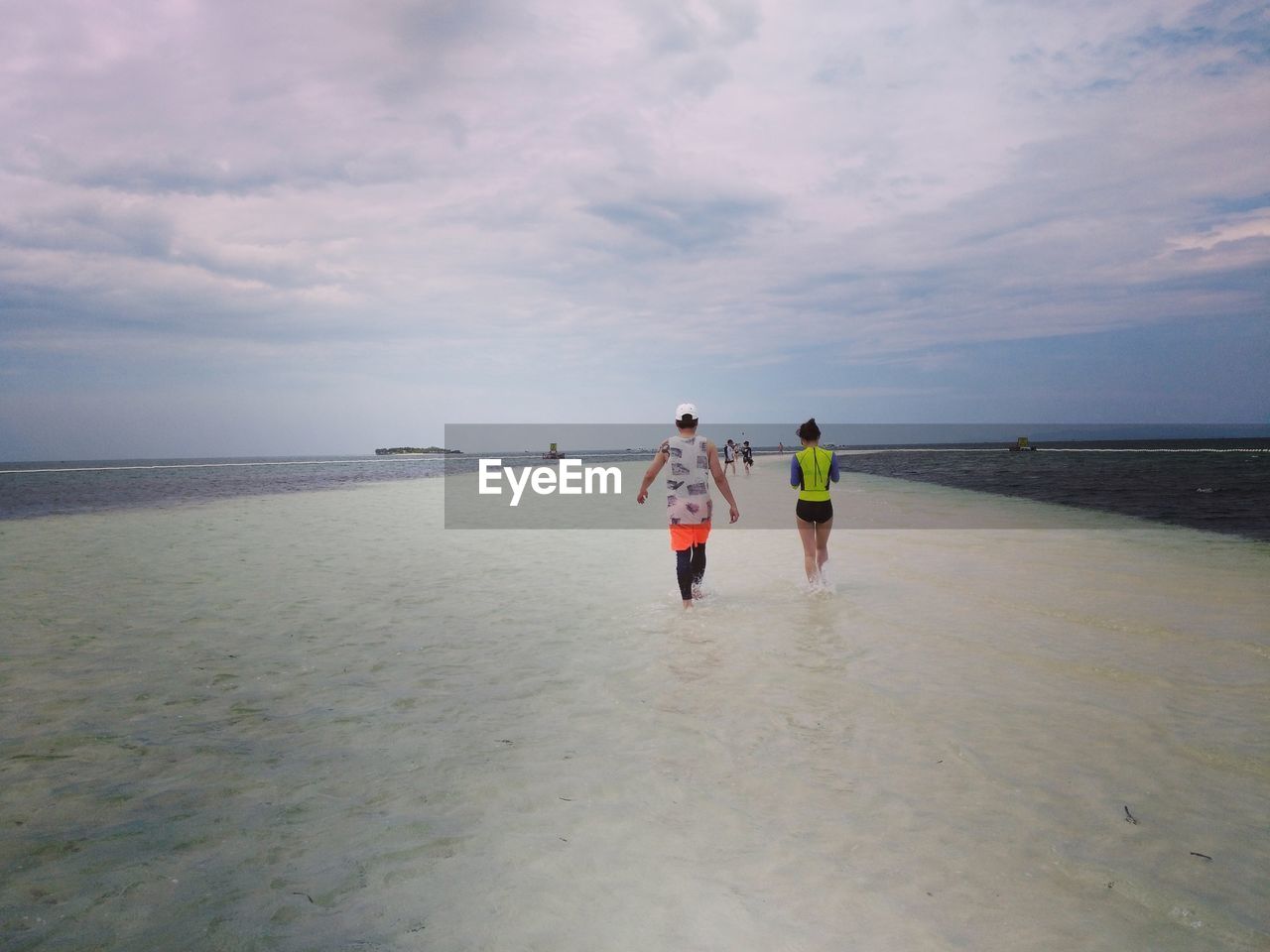 REAR VIEW OF CHILDREN WALKING ON BEACH