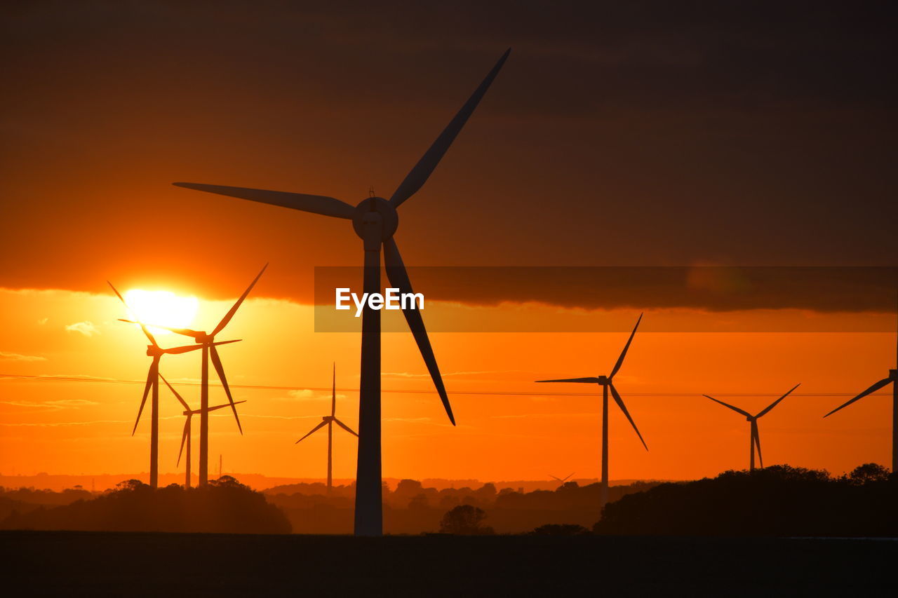 A bright red sunset through wind turbines