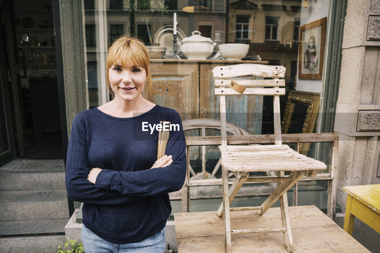 Portrait of smiling female owner standing outside antique shop