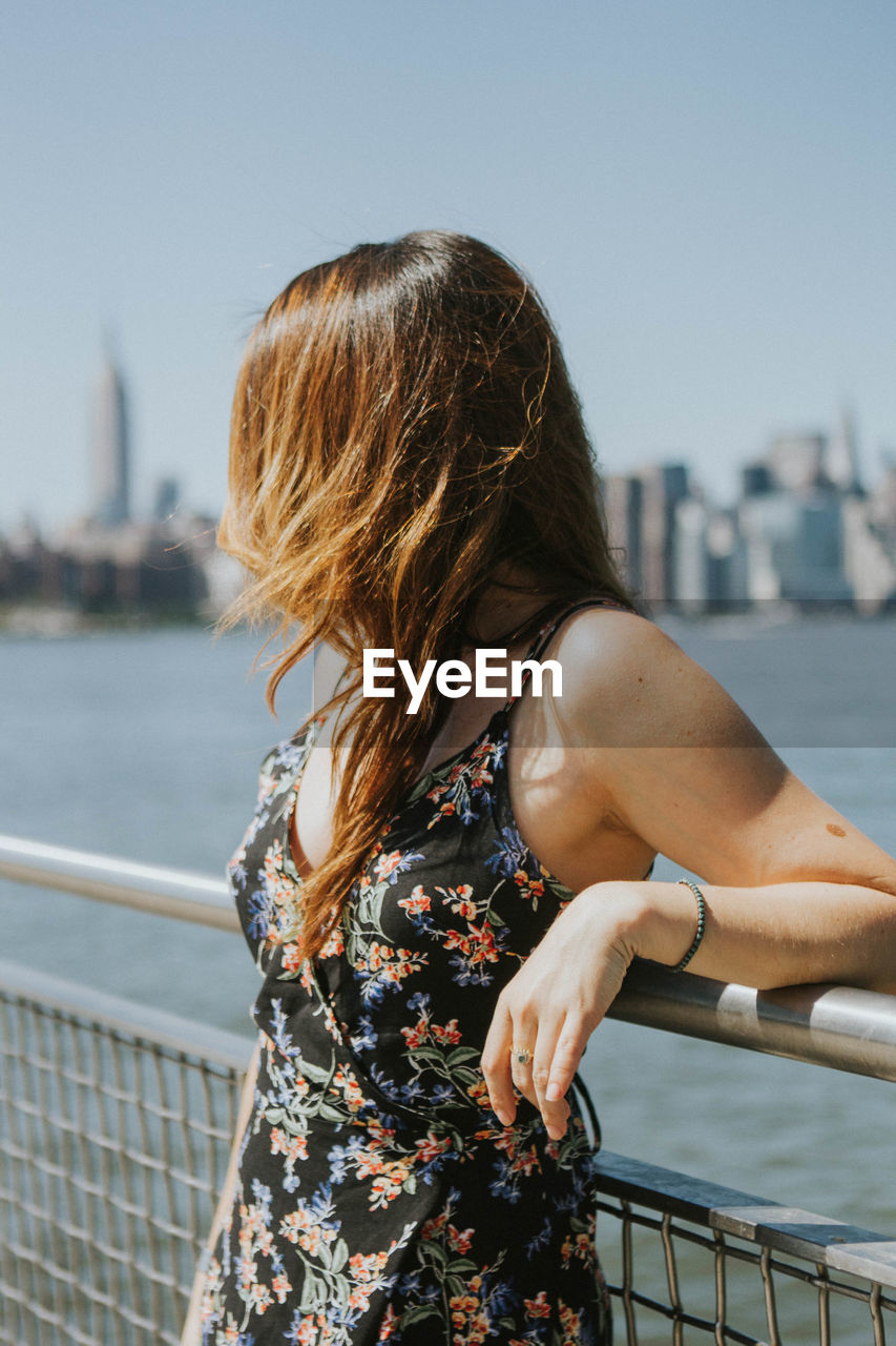 Woman standing by railing against river