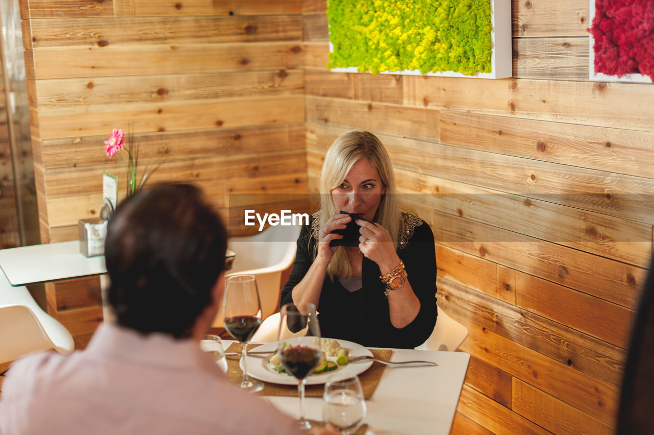 High angle view of man and woman at table against wooden wall in restaurant