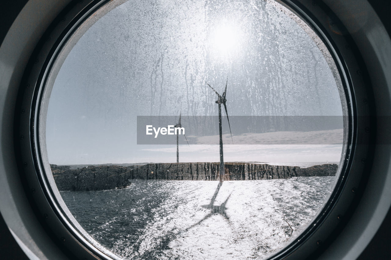 Scenic view of sky and wind turbines seen through glass window