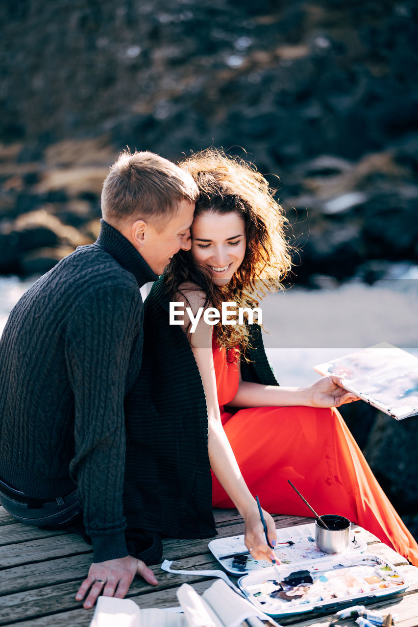 YOUNG COUPLE SITTING ON WOMAN