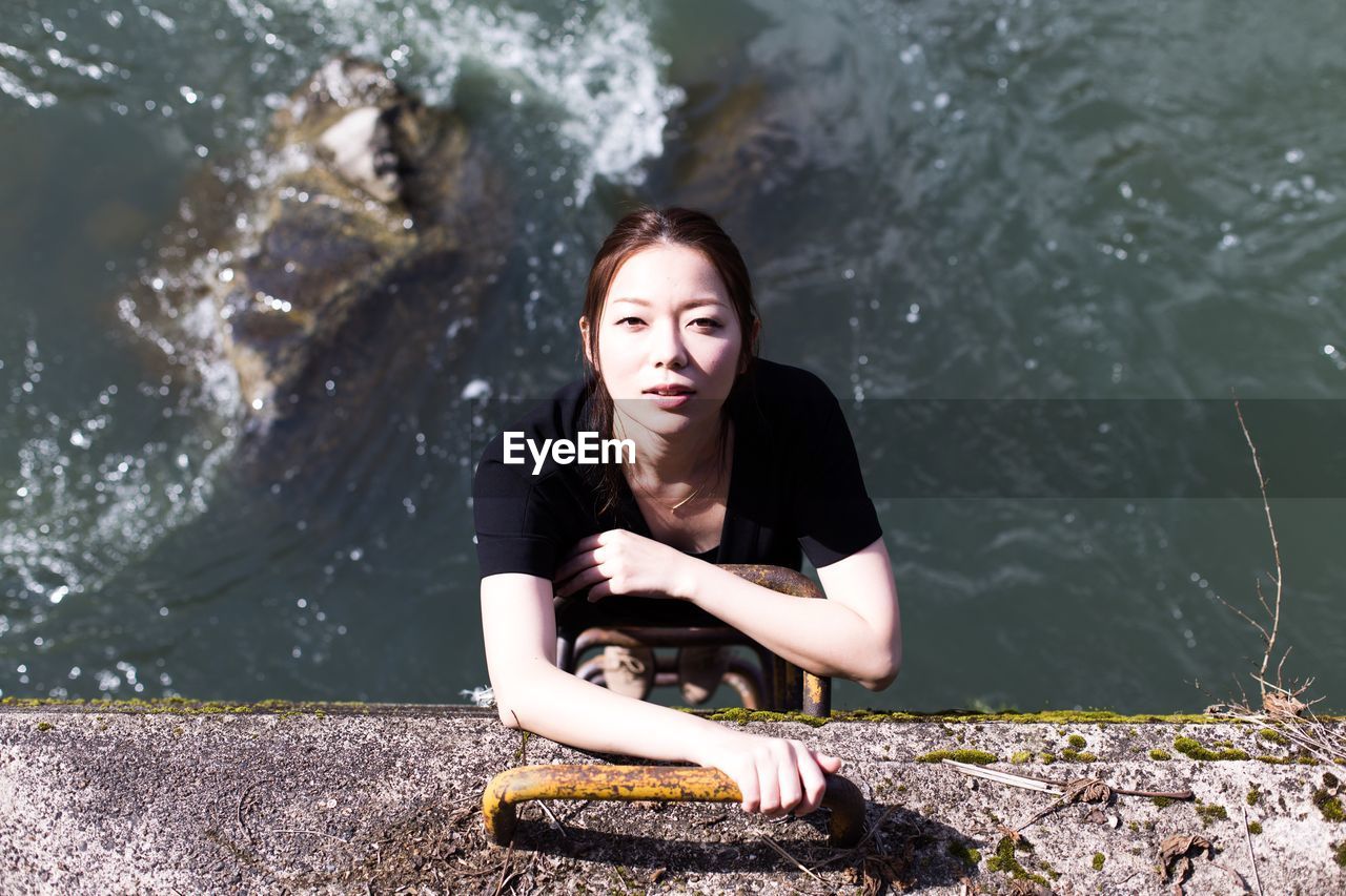 PORTRAIT OF YOUNG WOMAN SITTING IN WATER