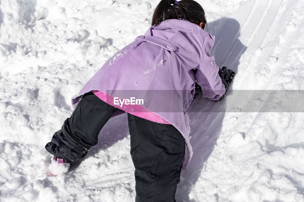 REAR VIEW OF WOMAN WITH SNOW ON FIELD