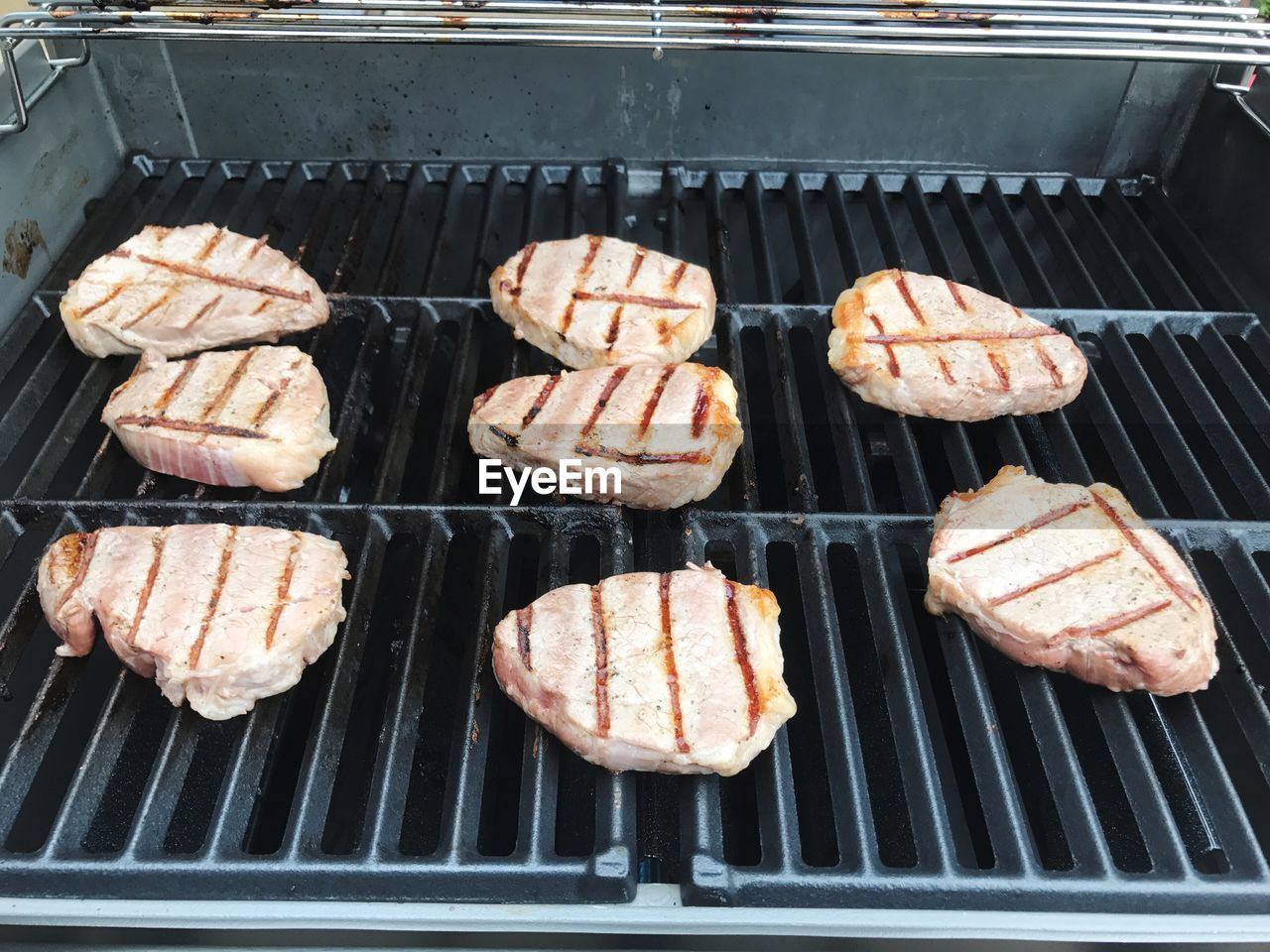 HIGH ANGLE VIEW OF MEAT COOKING ON GRILL