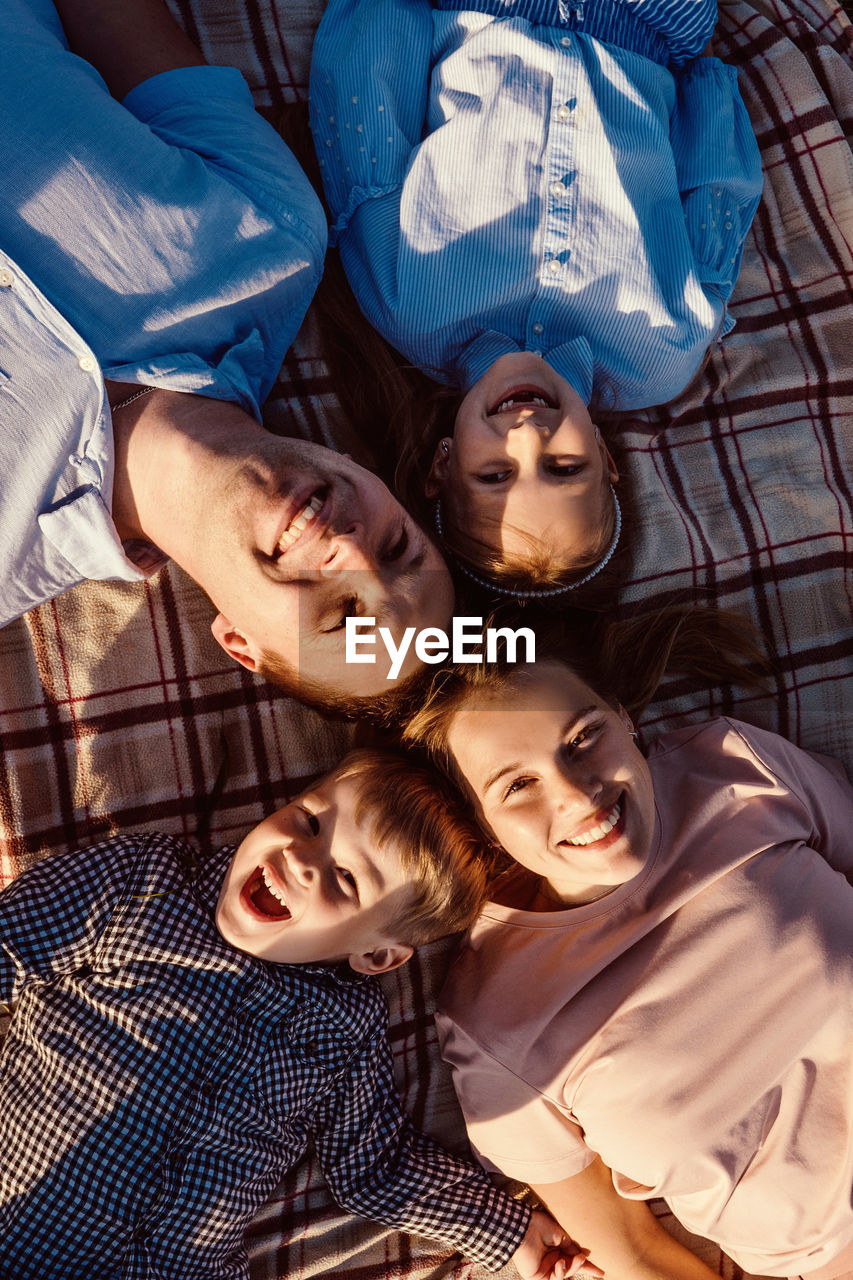 High angle portrait of smiling family lying on blanket in park