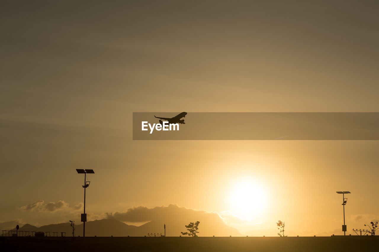 LOW ANGLE VIEW OF AIRPLANE FLYING IN SKY DURING SUNSET