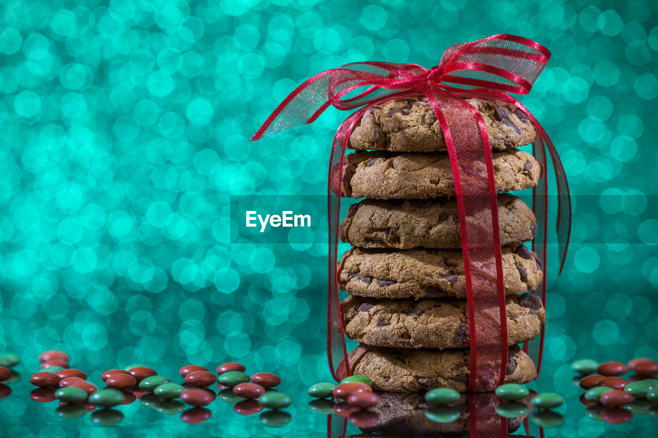 Close-up of cookies with candies on table against christmas lights