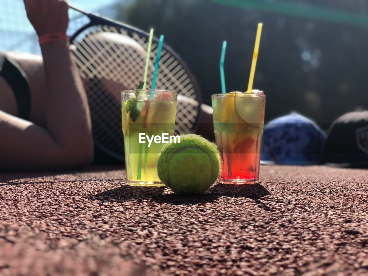 Close-up of tennis ball and drink in glasses at court