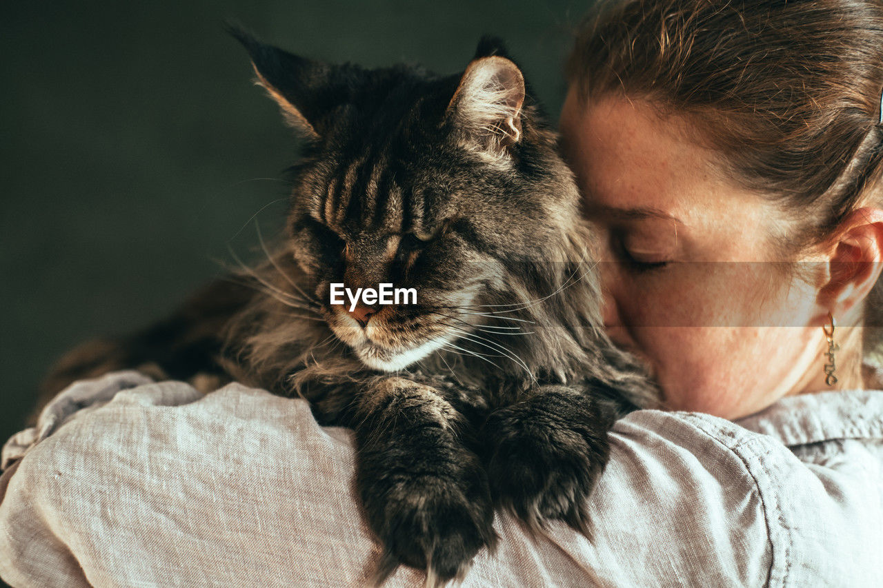Woman embracing pet cat at home