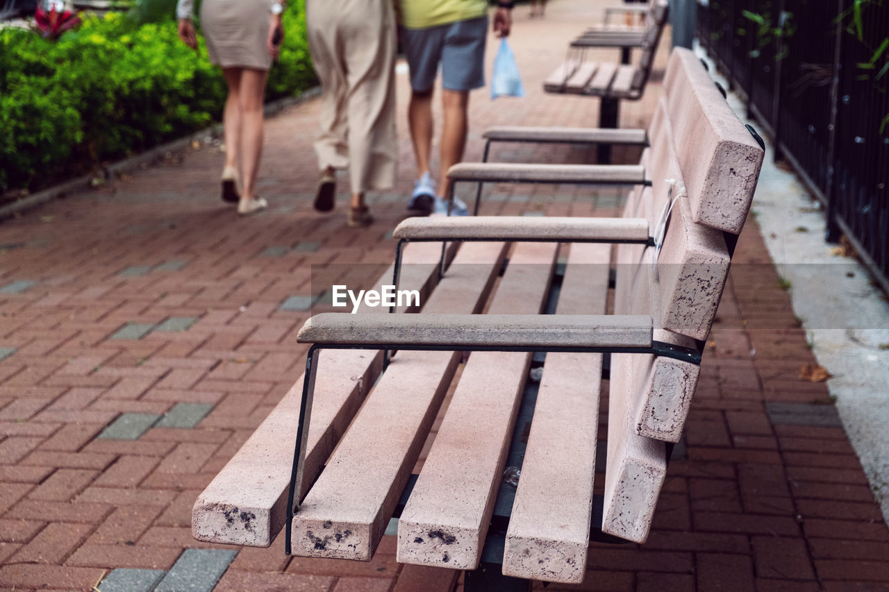 Benches and rear view of people walking on footpath