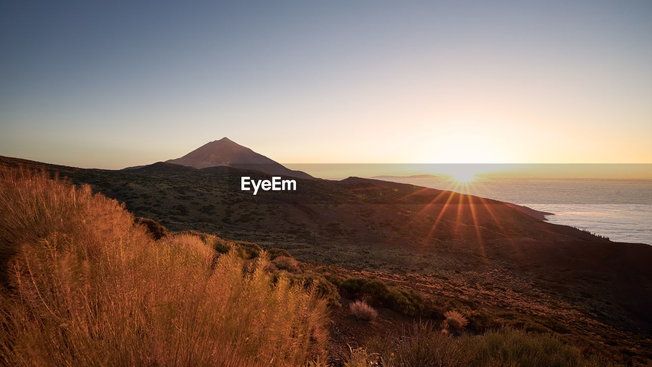 SCENIC VIEW OF MOUNTAINS AGAINST CLEAR SKY AT SUNSET