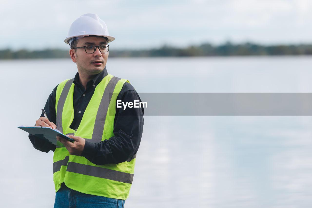 Portrait of young man standing by lake