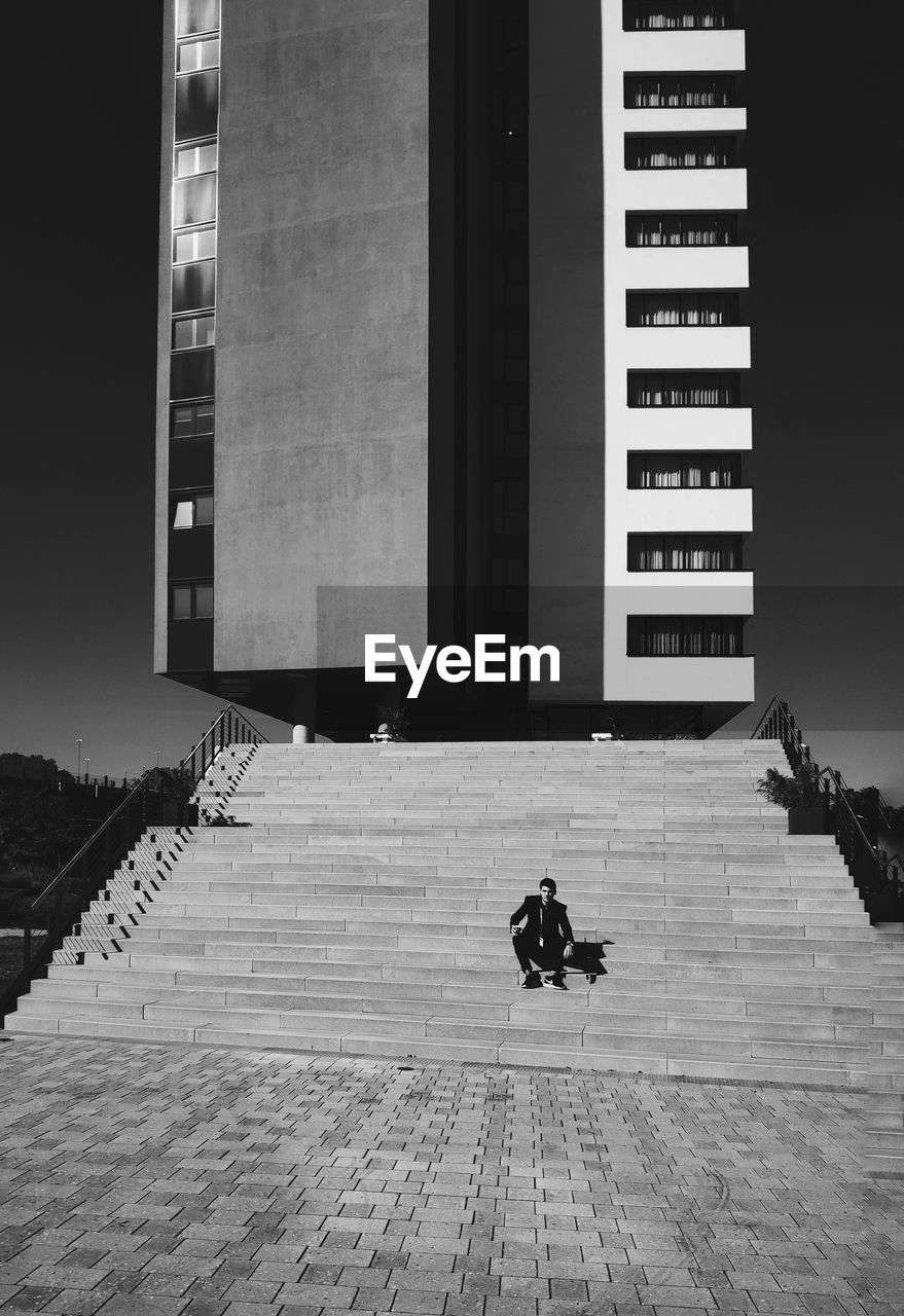 Man sitting on staircase against building