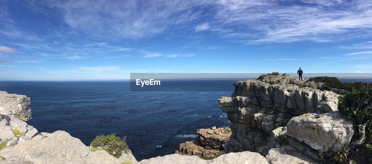 Rocks by sea against blue sky