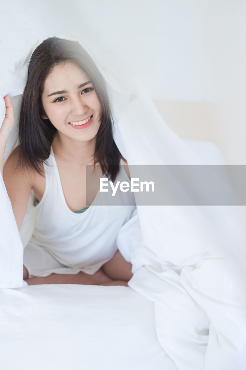 Portrait of smiling beautiful woman lying on bed at home
