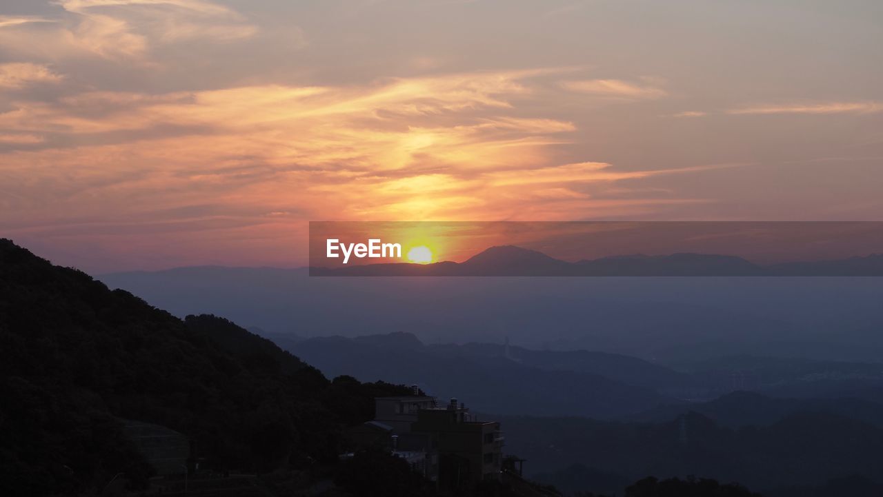 Scenic view of silhouette mountains against orange sky