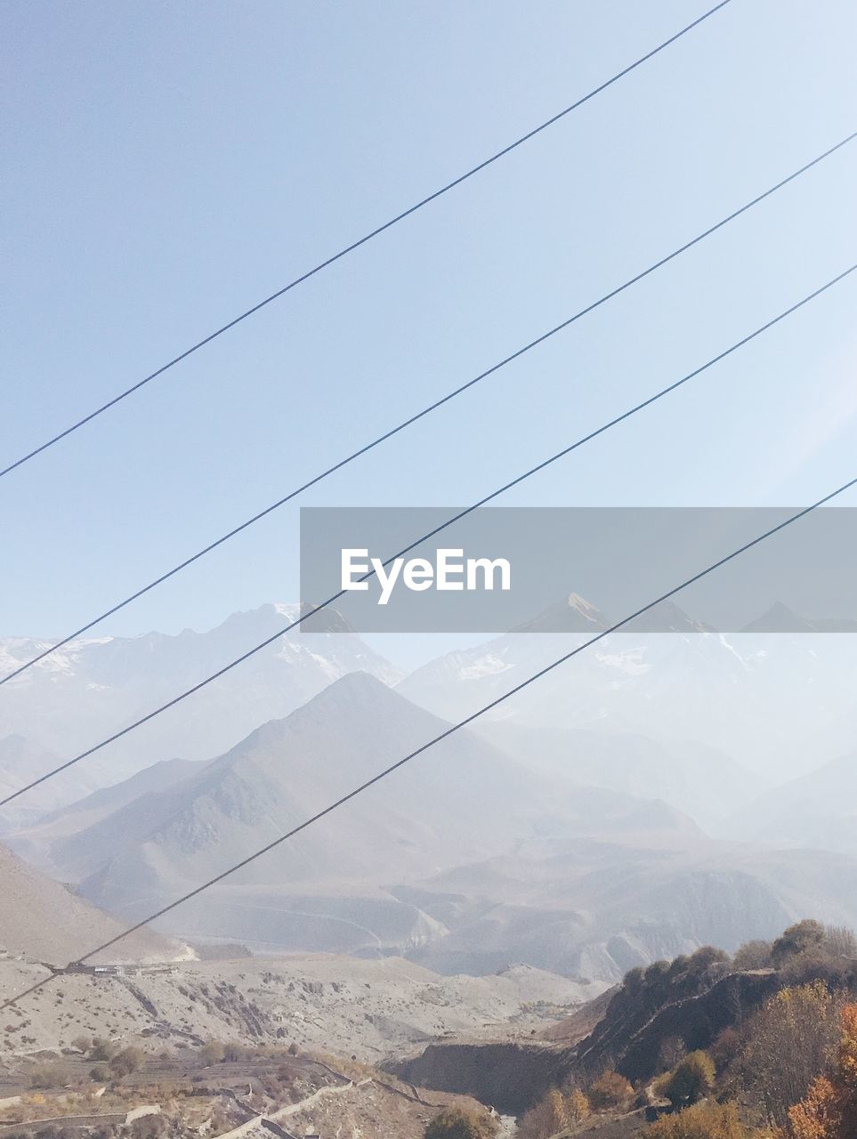 Scenic view of annapurna range against sky seen through cables