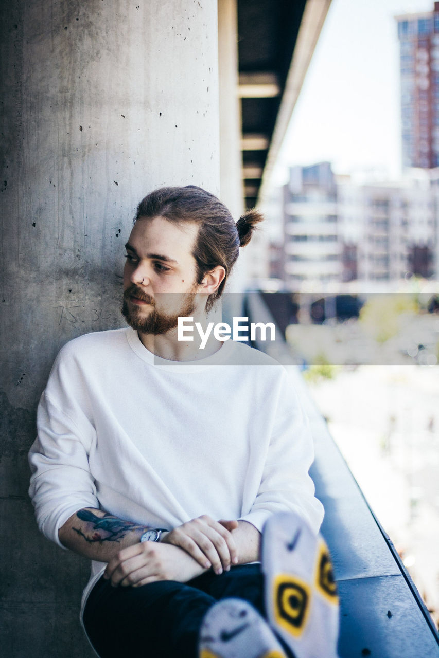 PORTRAIT OF SENIOR MAN SITTING IN CITY