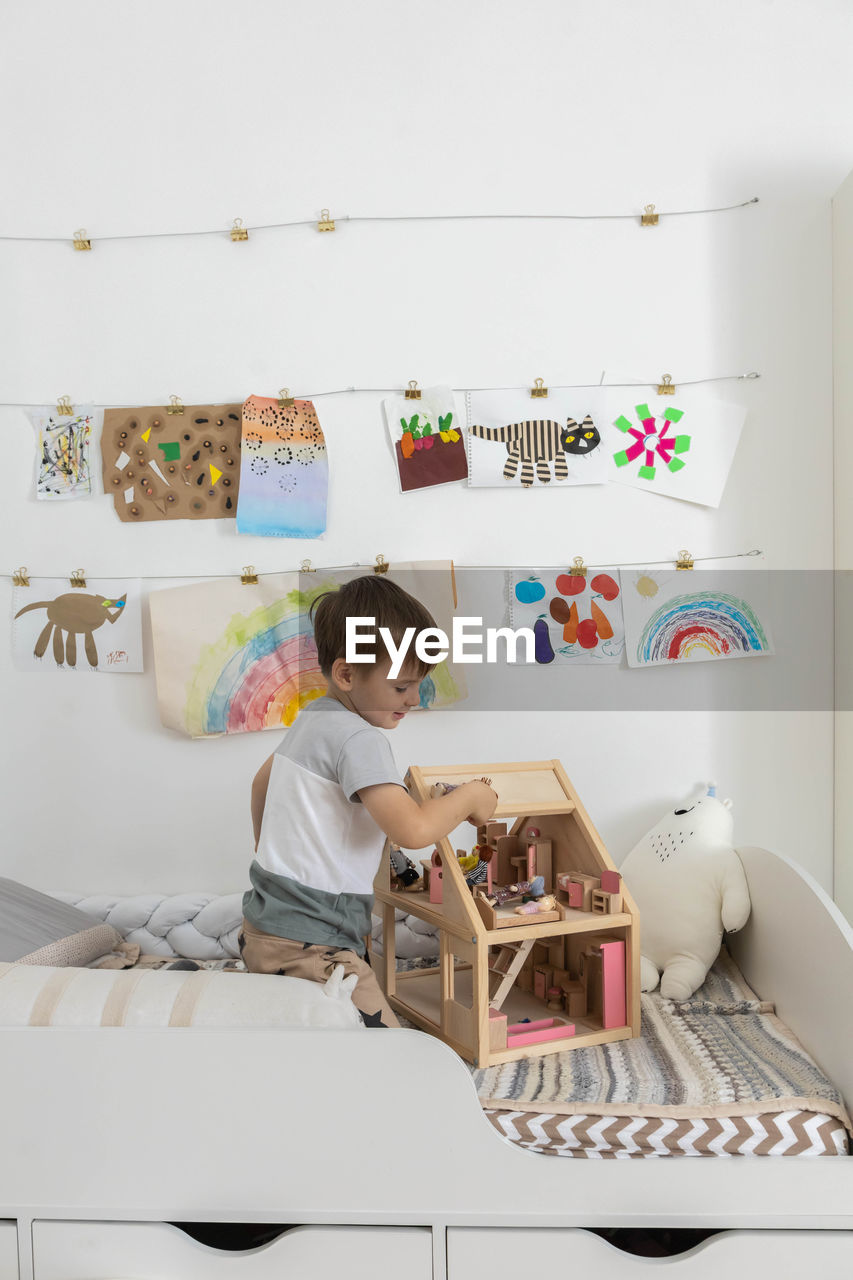 portrait of boy playing with teddy bear on bed at home