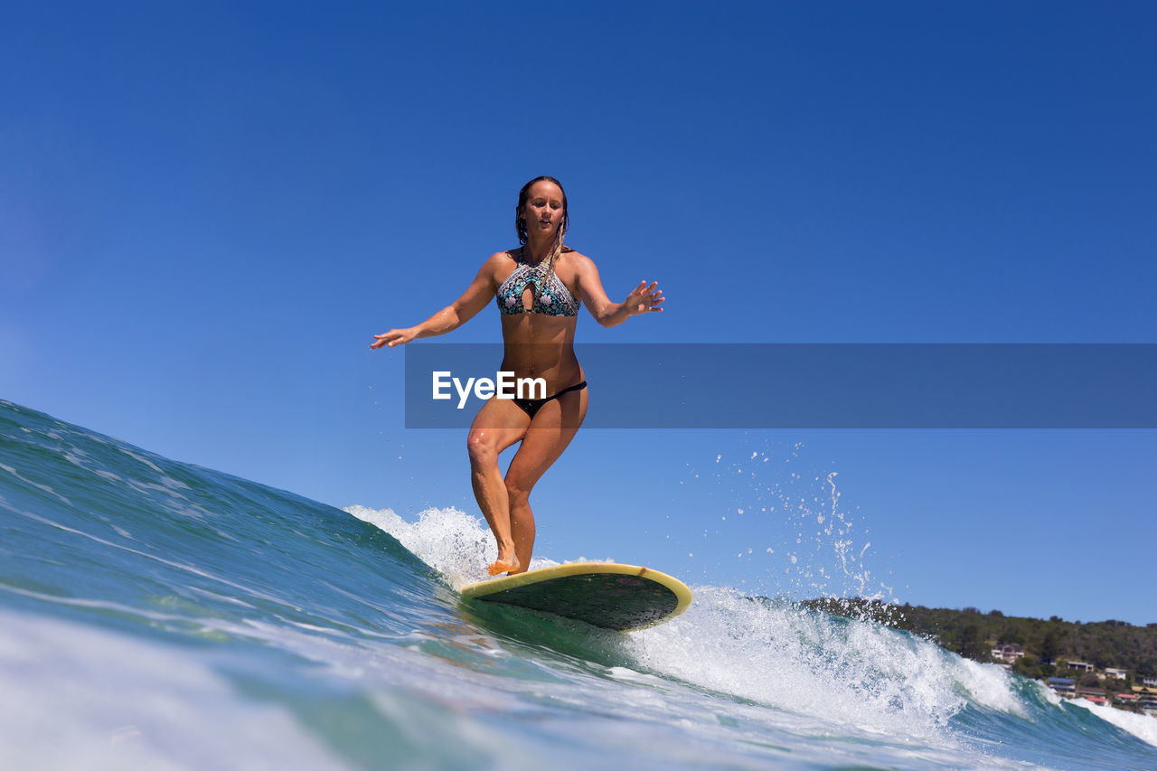 Woman surfing in sea against sky