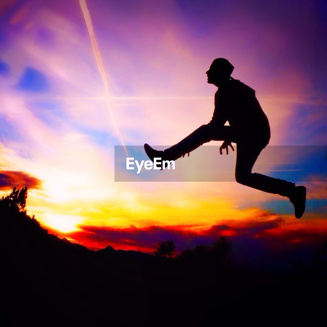 Silhouette woman jumping against cloudy sky at sunset