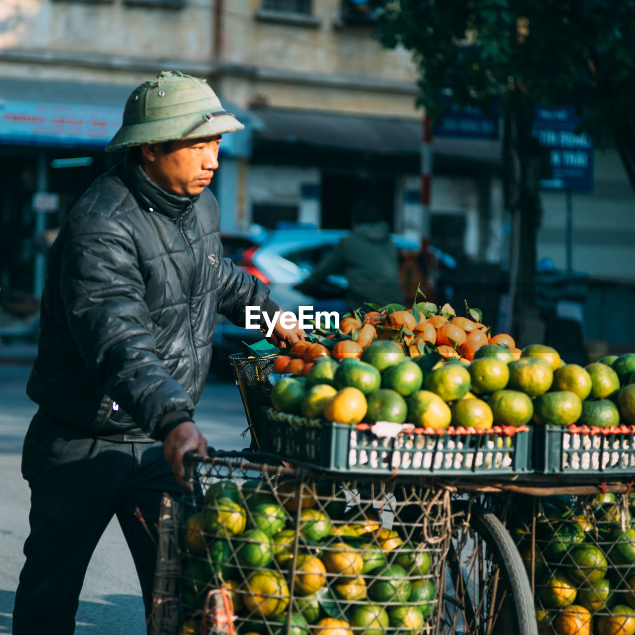 Male street vendor with fruits on bicycle in city